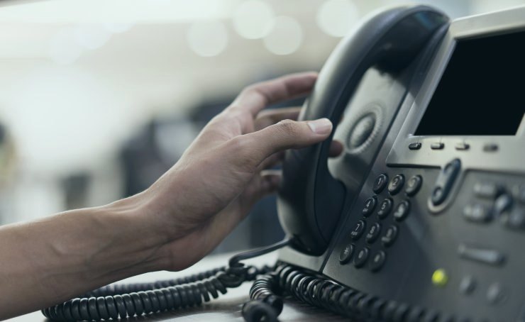 Hand picking up an office desk phone