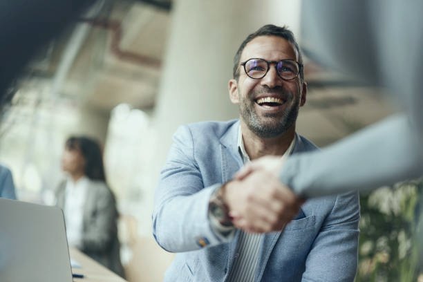 Smiling new hire shaking hands across a desk